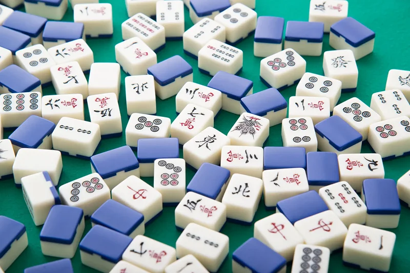 Infographic showing green table with a pile of white and blue dominoes, which are the traditional Chinese game of mahjong